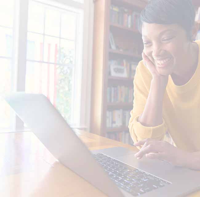 A person is smiling at something on their laptop.