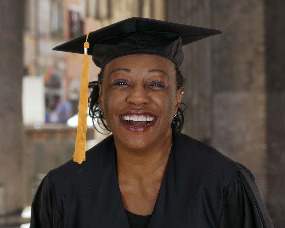 A person in graduation regalia smiling at the camera.