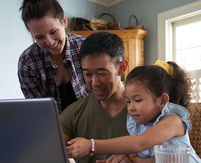 Two adults and a child looking at a laptop screen.