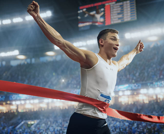 A person celebrating as they reach finish line tape.