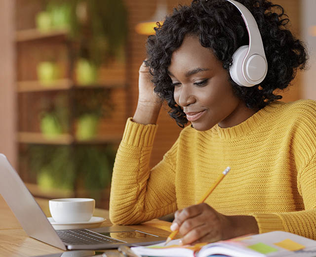 A person wearing headphones and looking at a laptop.