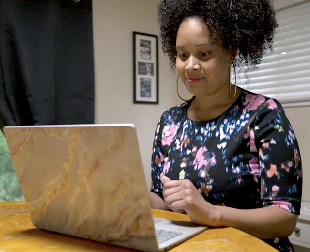 A person sitting and looking at a laptop screen.