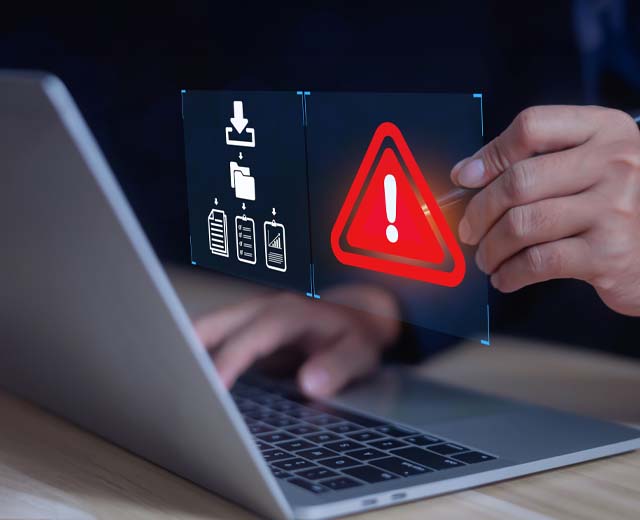 A red warning symbol floating above a person's hands on a laptop keyboard.