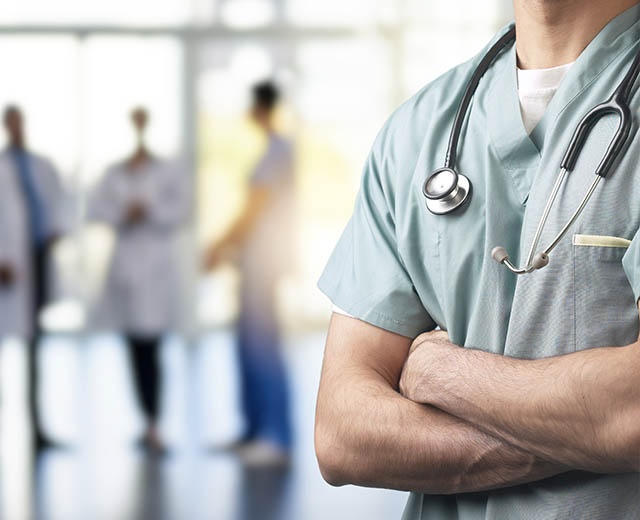 People in various medical uniforms standing in a hallway.