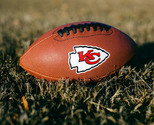 A football displaying the Kansas City Chiefs logo resting in the grass.