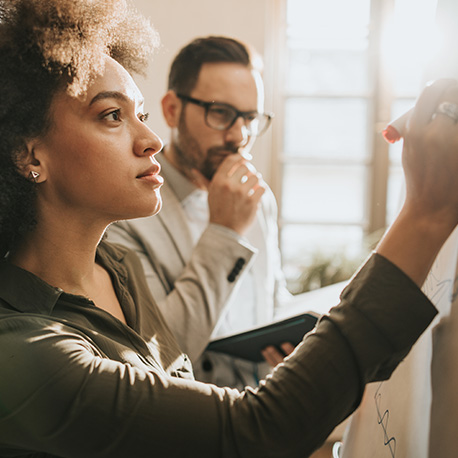 Two people looking at a whiteboard.